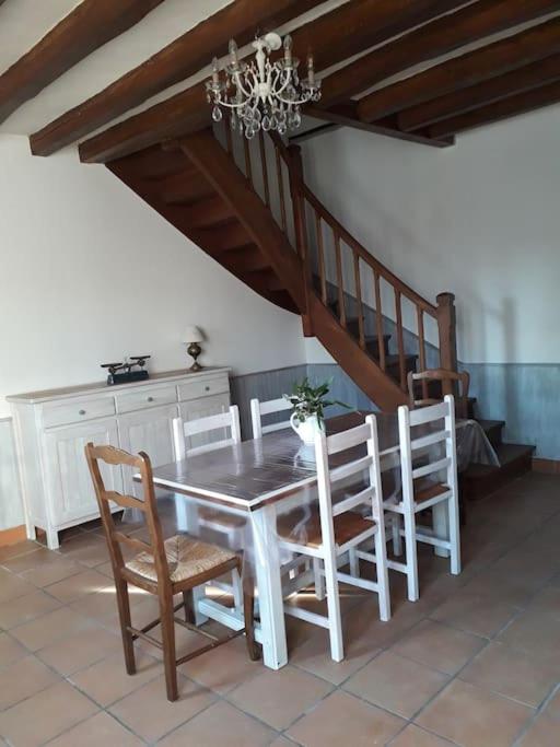 une salle à manger avec une table et des chaises et un escalier dans l'établissement Les guernouilles, à Mézières-en-Brenne