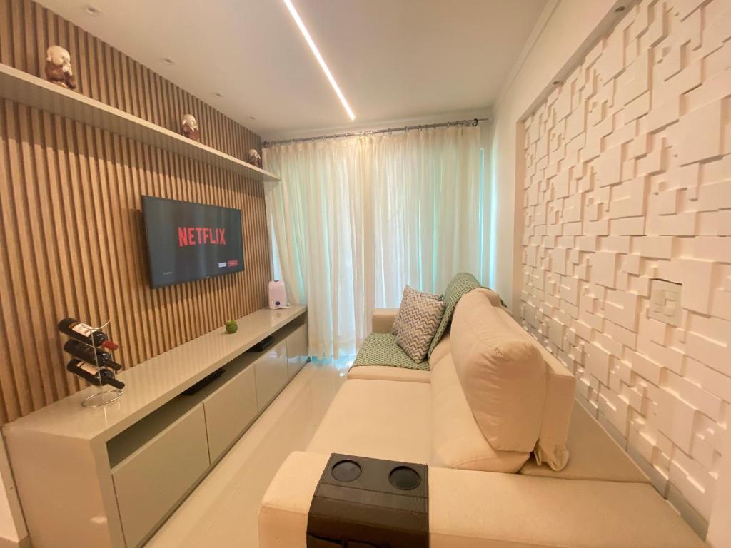 a living room with a couch and a tv at Elegante apto de 2/4 2004 in Goiânia