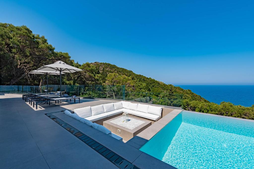 a swimming pool with a white couch and the ocean at Villa Anthelia in Pentátion