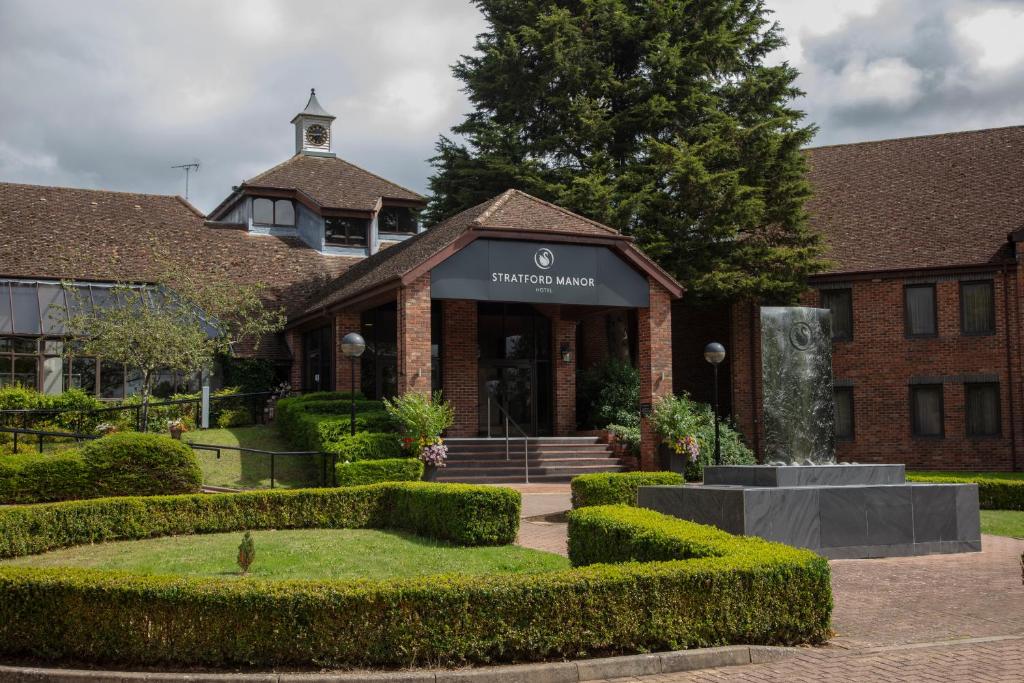 ein Gebäude mit einem Brunnen davor in der Unterkunft Stratford Manor Hotel in Stratford-upon-Avon