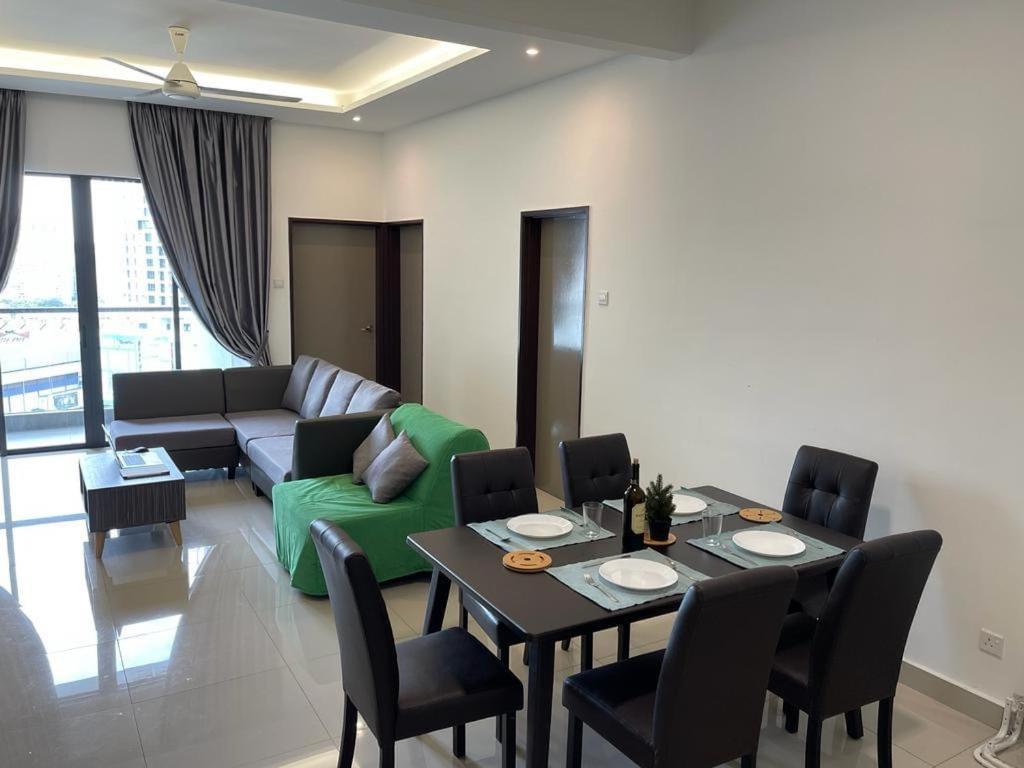 ein Wohnzimmer mit einem Tisch und einem grünen Sofa in der Unterkunft Skyville 8 @ Benteng in Kuala Lumpur
