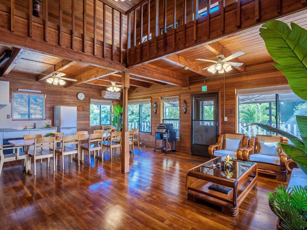 a living room with wooden ceilings and a dining room at Kariyushi Condominium Resort Yuudekiya in Onna