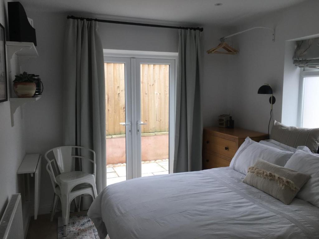 a bedroom with a bed and a sliding glass door at Cedar Shade Cottage Ensuite Private Annexe with Parking in Sidmouth
