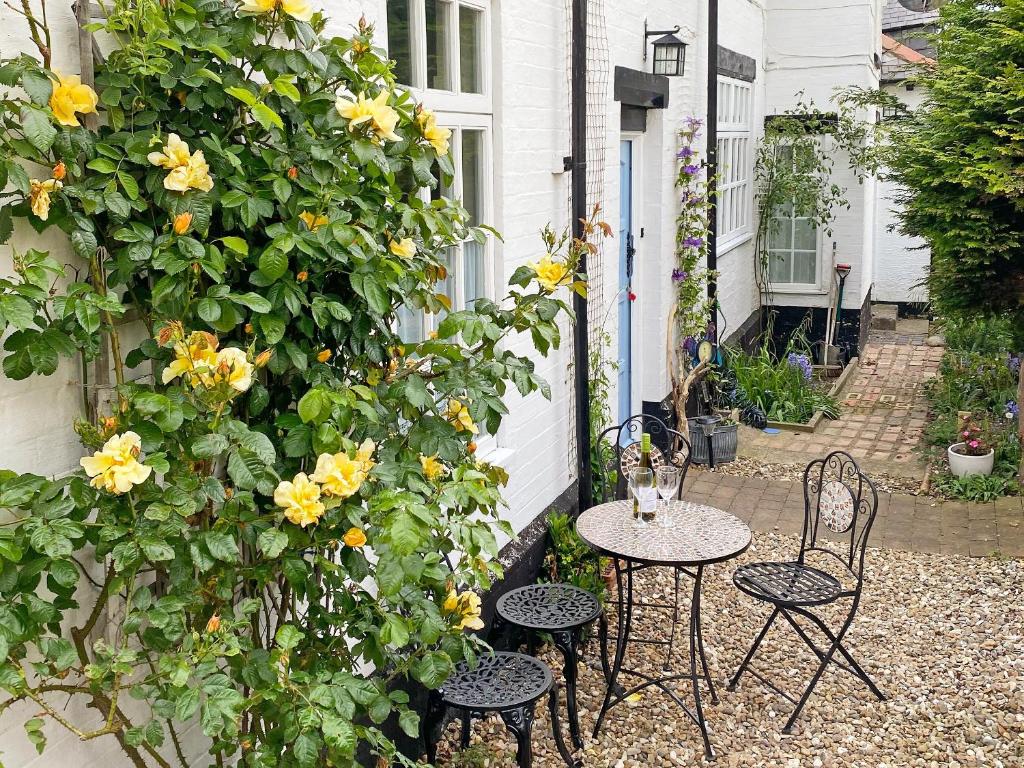 ホーンジーにあるGarden Cottageのパティオ(椅子2脚、黄色い花のテーブル付)