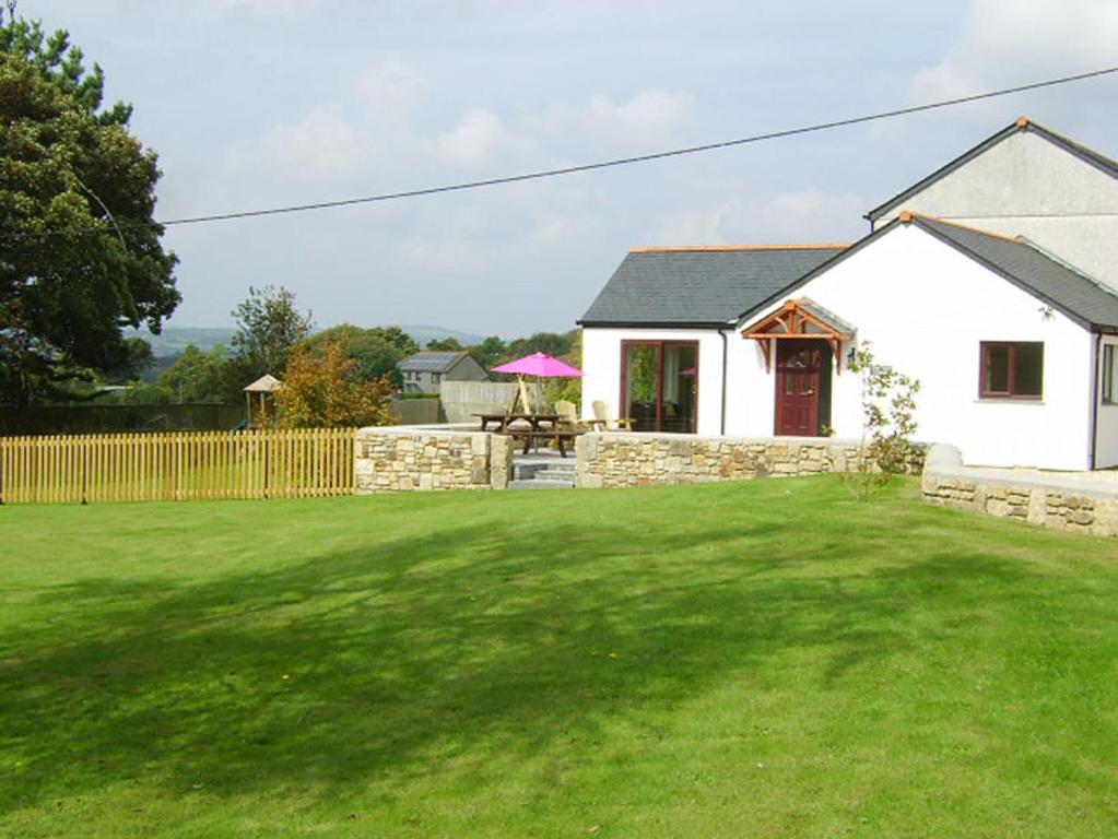 a white house with a yard with a green lawn at Tregarthen Cottage in Perranuthnoe