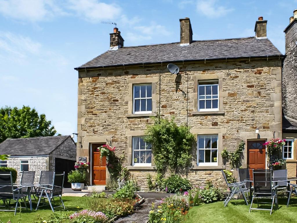 a stone house with chairs in the garden at Beech Cottage - Uk44731 in Hartington