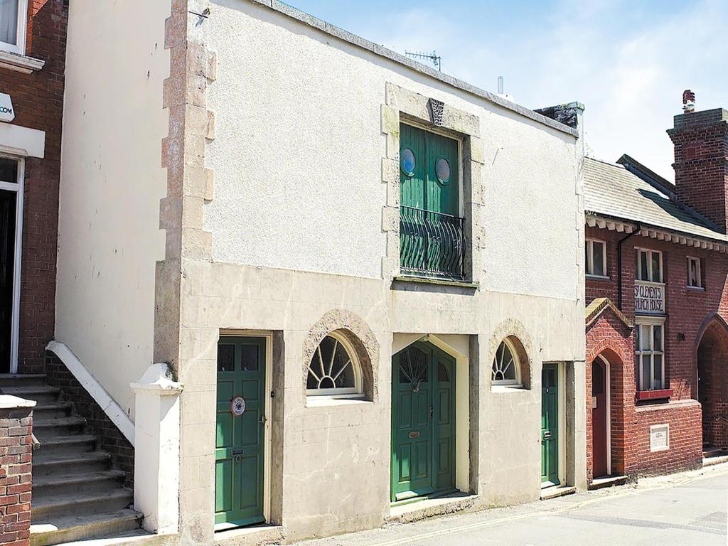 an old brick building with green doors and a balcony at Seagulls Nest in Hastings