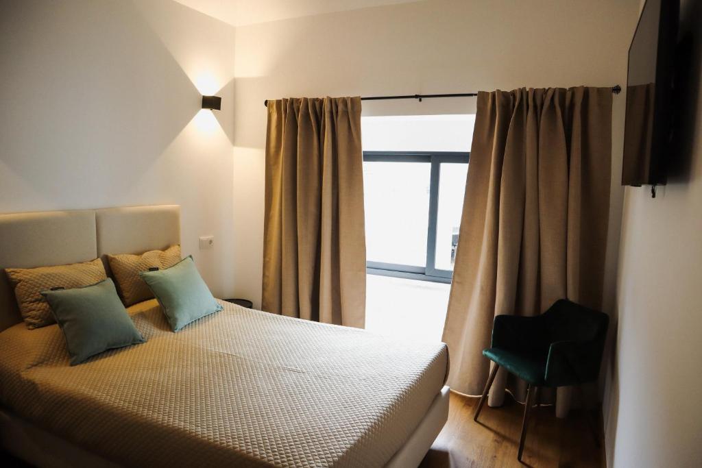 een slaapkamer met een bed met een raam en een stoel bij PATE'O Hostel & Suites in Ovar