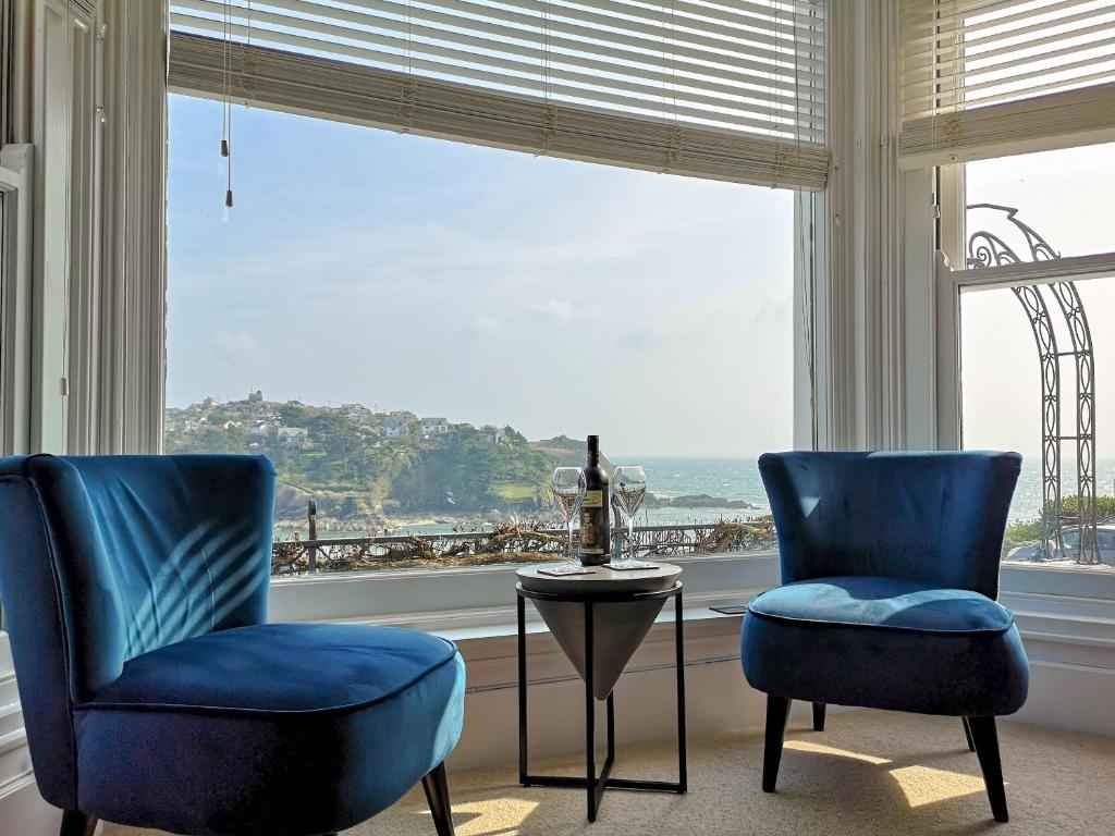 two blue chairs and a table in front of a window at Seascape - St Catherines Court in Fowey