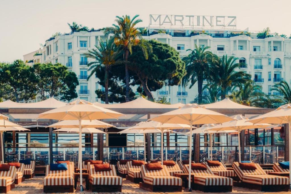 a group of chairs and umbrellas in front of a hotel at Hôtel Martinez, in The Unbound Collection by Hyatt in Cannes