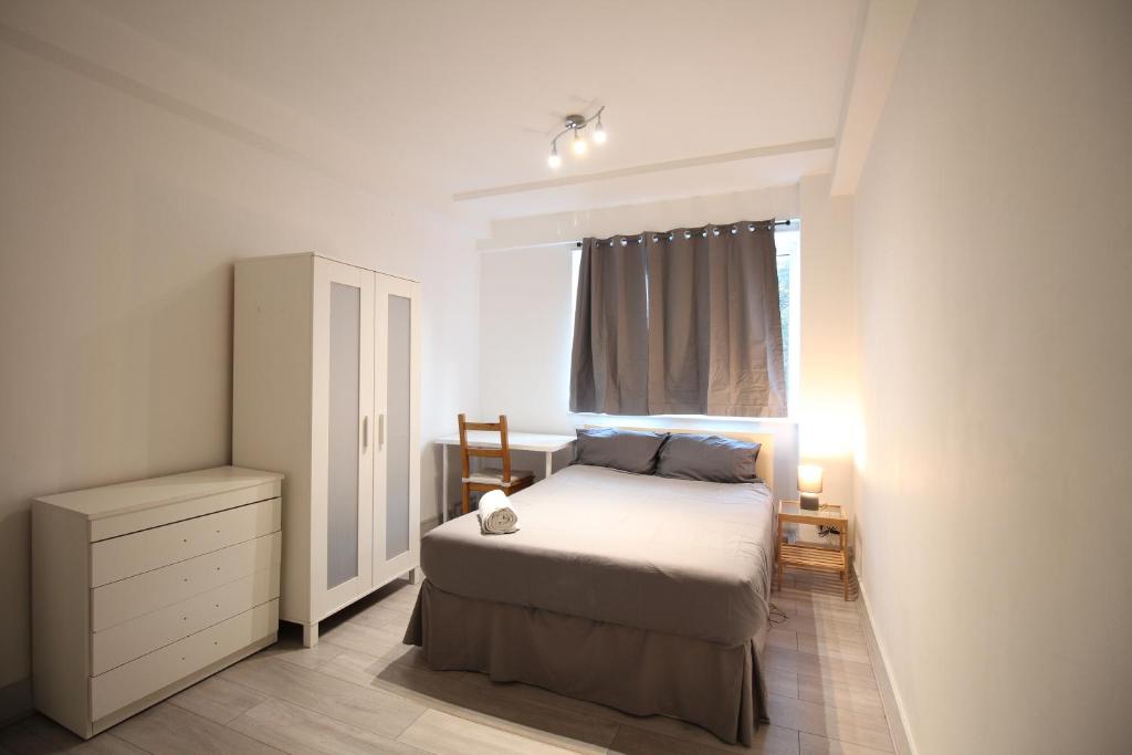a bedroom with a bed and a dresser and a window at Central London Maida Vale 4 or 5 bed spacious apartment in London