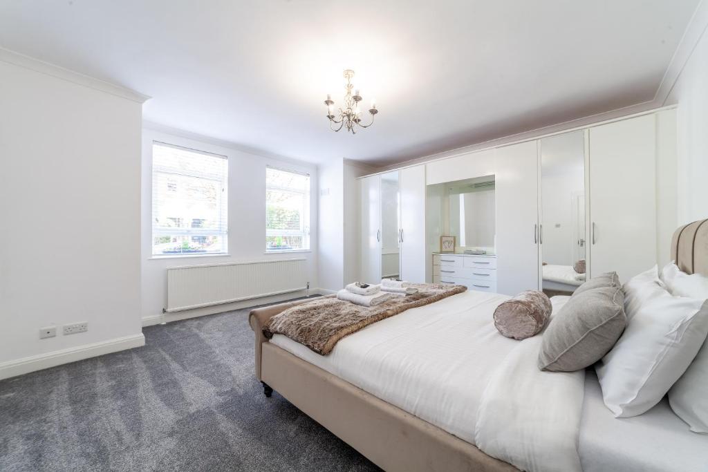 a white bedroom with a large bed and windows at Fantastic 2BR flat wpriv Gdn, Crouch End in London