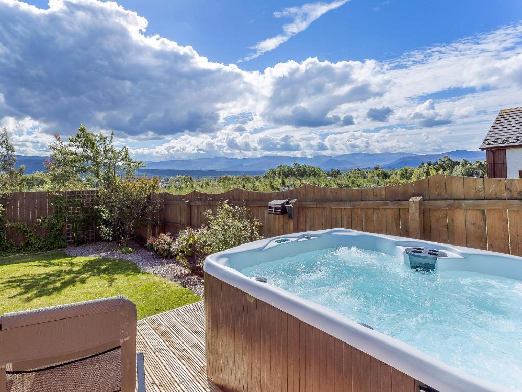 a hot tub in a backyard with a fence at The Lookout in Aviemore