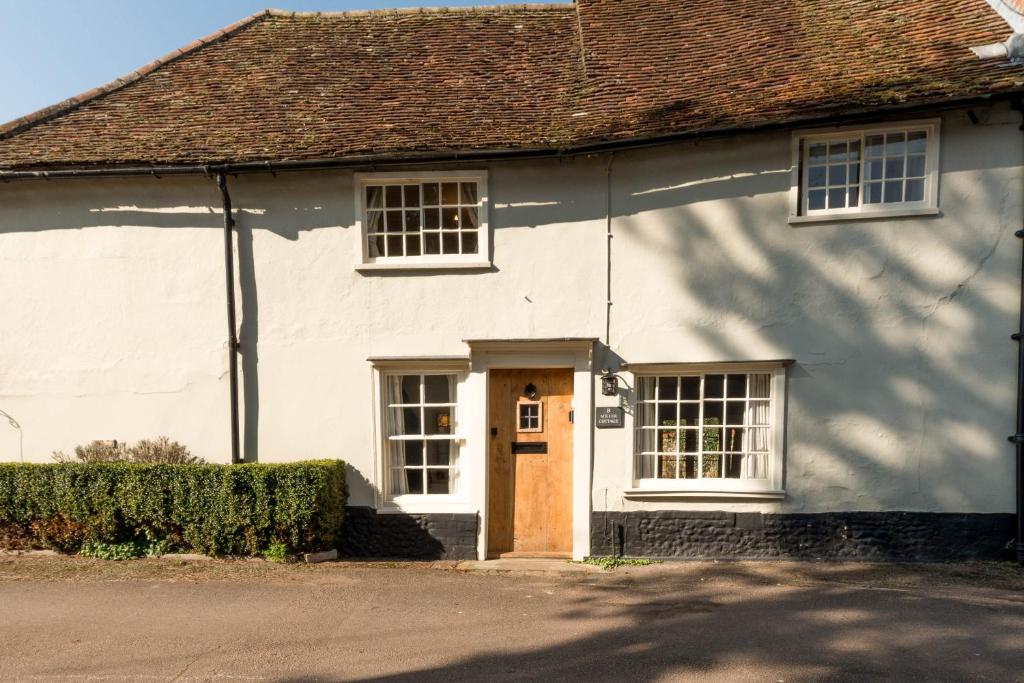 a white house with a brown door at Miller Cottage a luxury 1550's cottage in the Historic centre of Saffron Walden in Saffron Walden