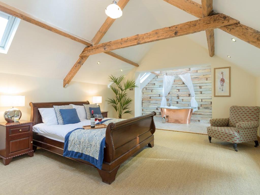 a bedroom with a bed and a chair and a tub at The Coach House in Ridingmill