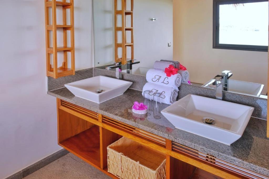 eine Badezimmertheke mit zwei Waschbecken und einem Spiegel in der Unterkunft ANJARA LODGE Villa de 3 chambres in Nosy Be