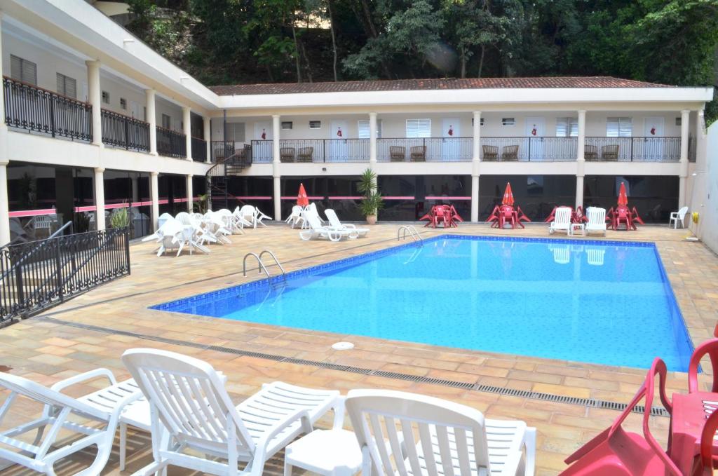 ein Hotel mit Pool, Stühlen und einem Gebäude in der Unterkunft Hotel São Luiz in Águas de Lindóia