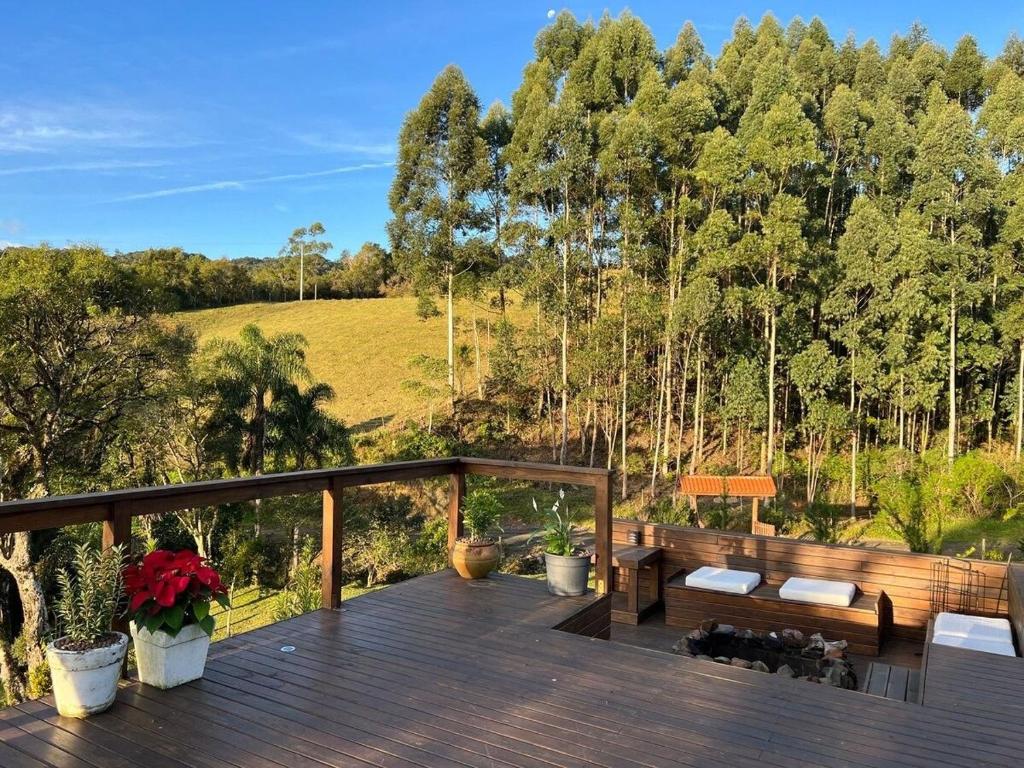 een houten terras met een bank en enkele bomen bij Quinta da Serra - Onde o charme se mistura com a natureza in Rancho Queimado