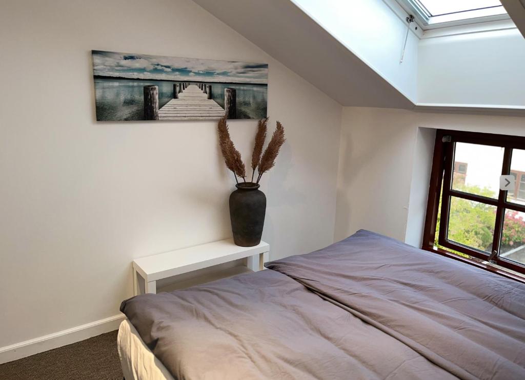 a bedroom with a bed and a vase on a table at DreamCenter Ballerup Boulevard in Ballerup