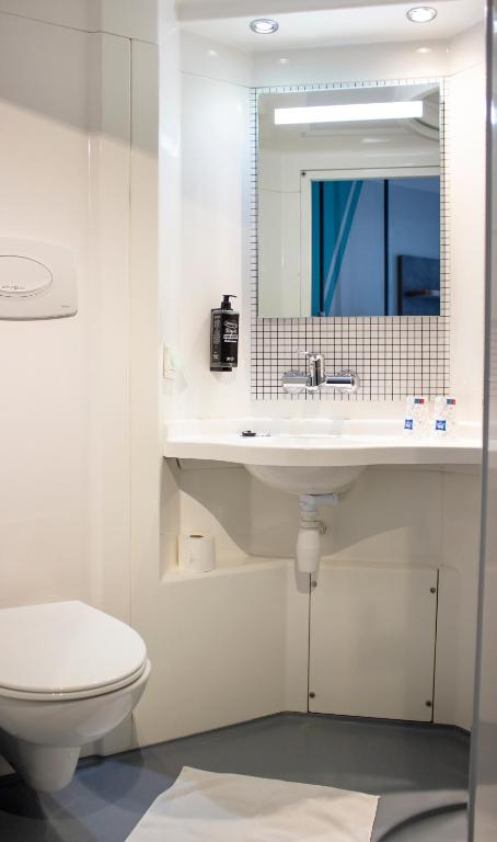 La salle de bains blanche est pourvue d&#39;un lavabo et de toilettes. dans l&#39;établissement ibis budget Lunel Porte de Camargue, à Aimargues