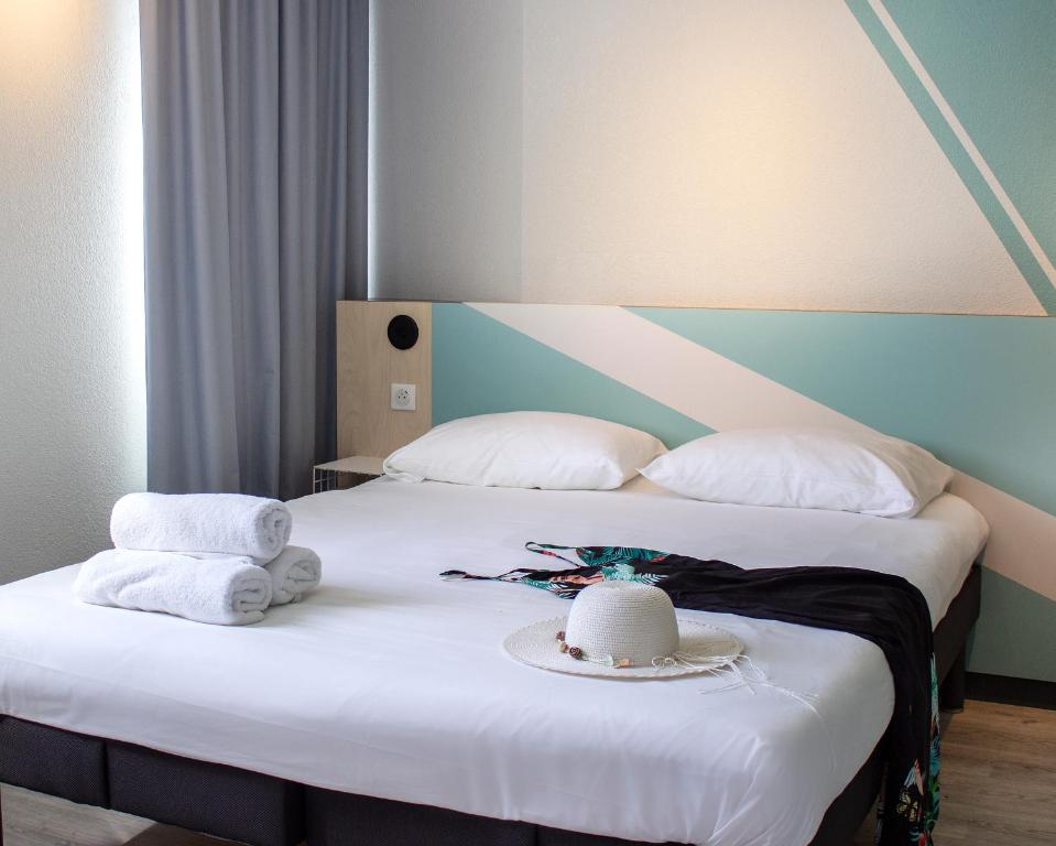 - un lit avec 2 serviettes et un chapeau dans l&#39;établissement ibis budget Lunel Porte de Camargue, à Aimargues