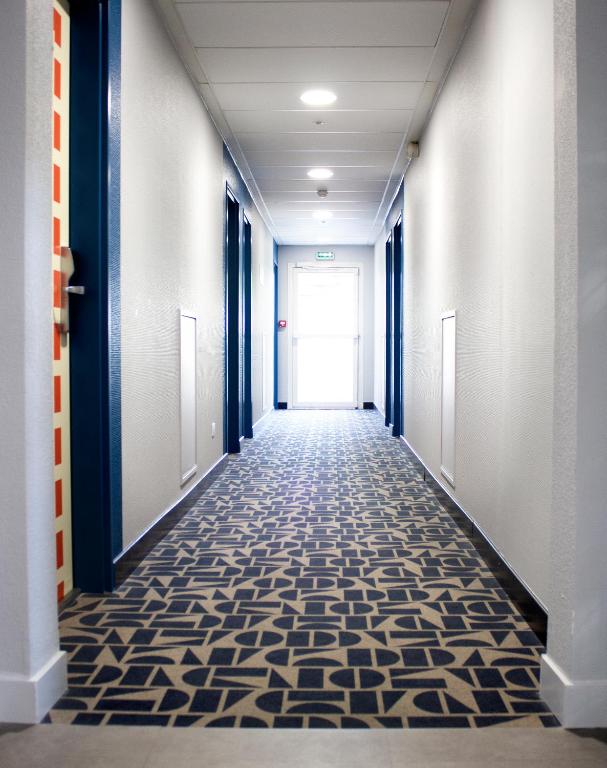 un couloir d&#39;un immeuble de bureaux avec une porte dans l&#39;établissement ibis budget Lunel Porte de Camargue, à Aimargues
