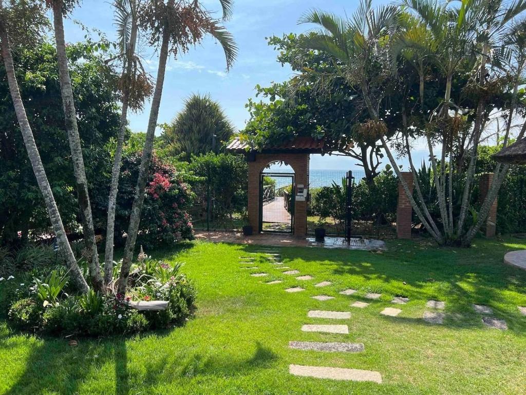 un jardín con un sendero de piedra y un cenador en Casa pé na areia em praia paradisíaca en Balneário Camboriú