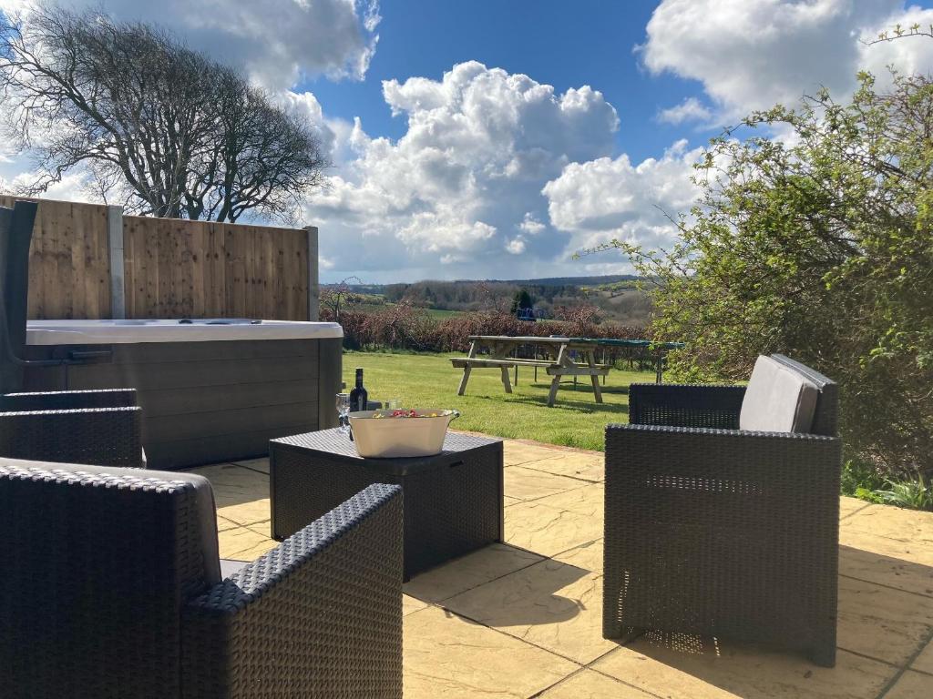 a patio with three chairs and a table and a tub at The Coach House in Llanasa