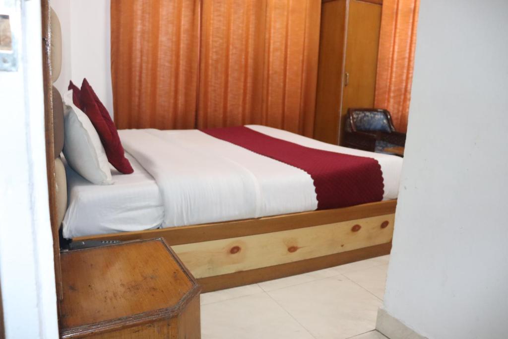 a bedroom with a bed with white sheets and red pillows at Hotel Tourist Home By palak Hospitality in Mussoorie