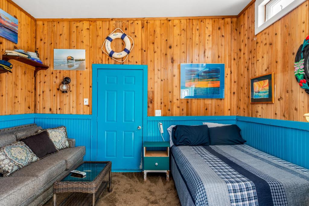 Dormitorio azul con cama y sofá en The Blue Parrot Guest House, en Ocean Beach