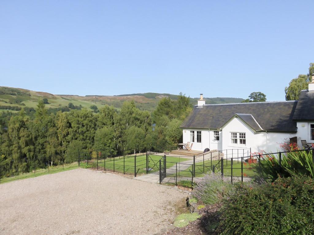 a white house with a fence in front of it at Tummel Cottage in Foss
