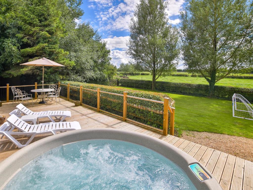 a hot tub on a deck with chairs and a table at 1 Luckington Stables-w8321 in Holcombe