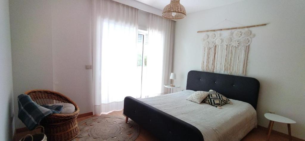 a bedroom with a bed and a large window at Figueira Holidays in Buarcos
