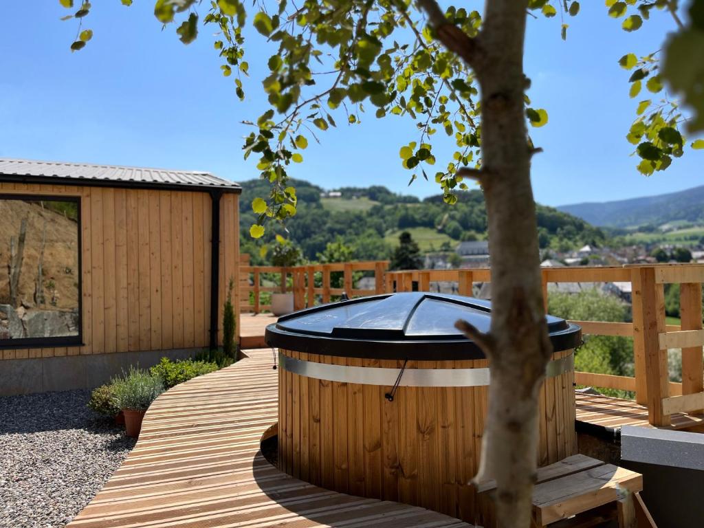 a hot tub on a wooden deck with a tree at Domaine des Constellations - Gîtes & Bains Nordiques in Orbey