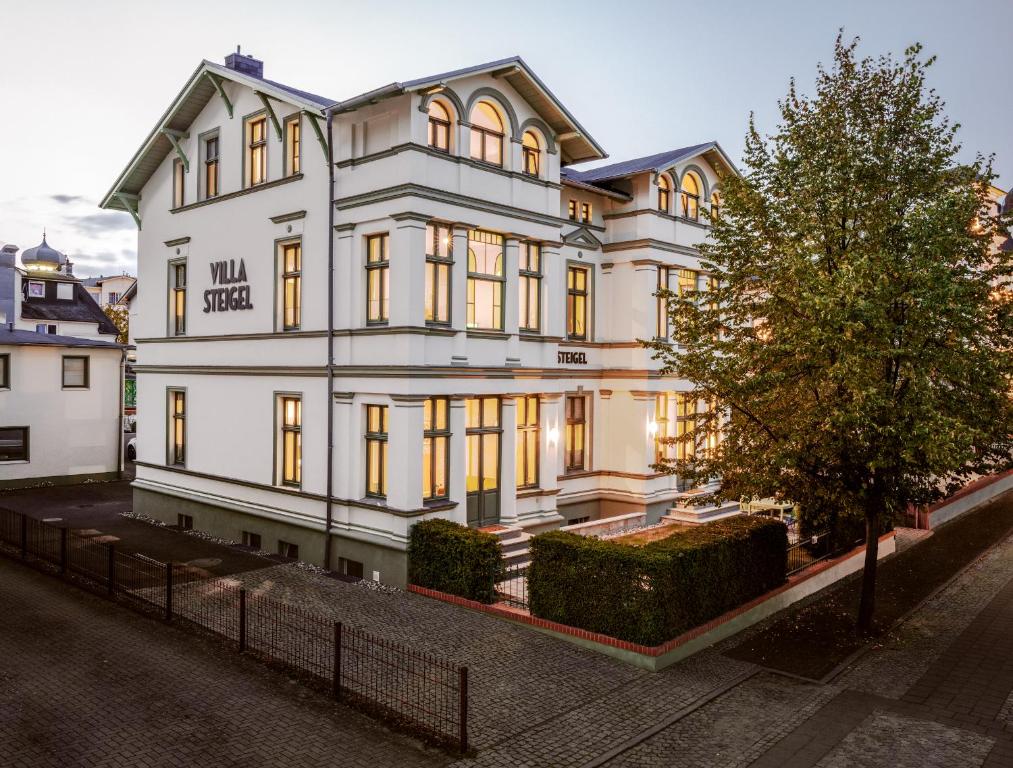 a large white building with a tree in front of it at OSTKÜSTE - Villa Steigel Design Apartments in Ahlbeck