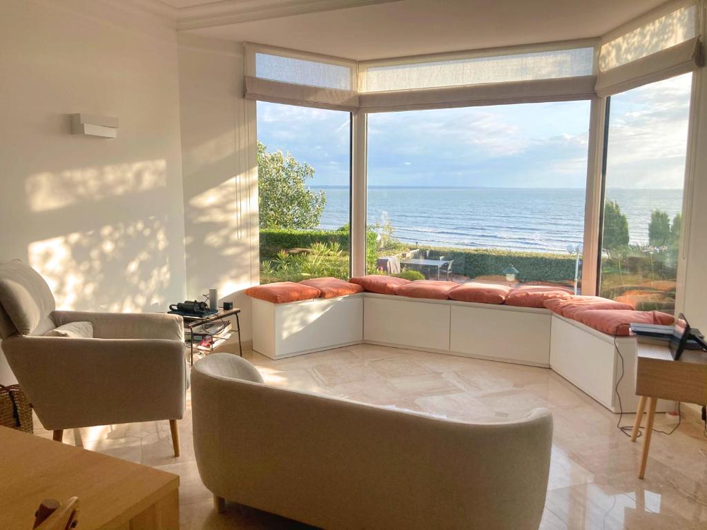 a living room with a large window with a view of the ocean at Manava Villa vue mer et Mont Saint Michel piscine intérieure in Saint-Jean-le-Thomas