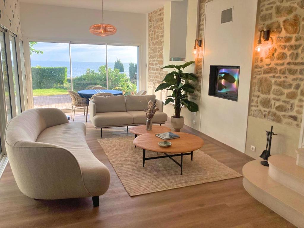 a living room with a couch and a table at Manava Villa vue mer et Mont Saint Michel piscine intérieure in Saint-Jean-le-Thomas