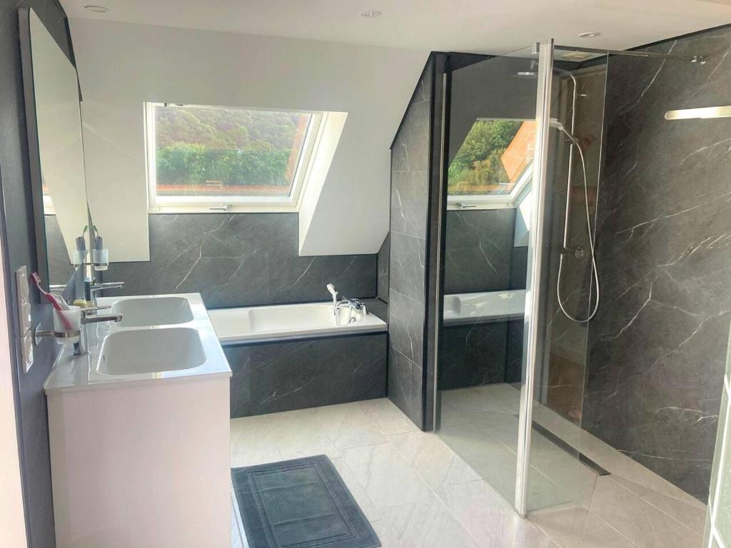 a bathroom with a tub and a sink and a shower at Manava Villa vue mer et Mont Saint Michel piscine intérieure in Saint-Jean-le-Thomas