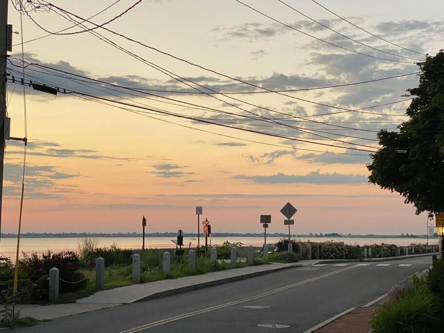 an empty road next to a beach at sunset at Historic 2 Bedroom with marble baths and water views in Newburyport