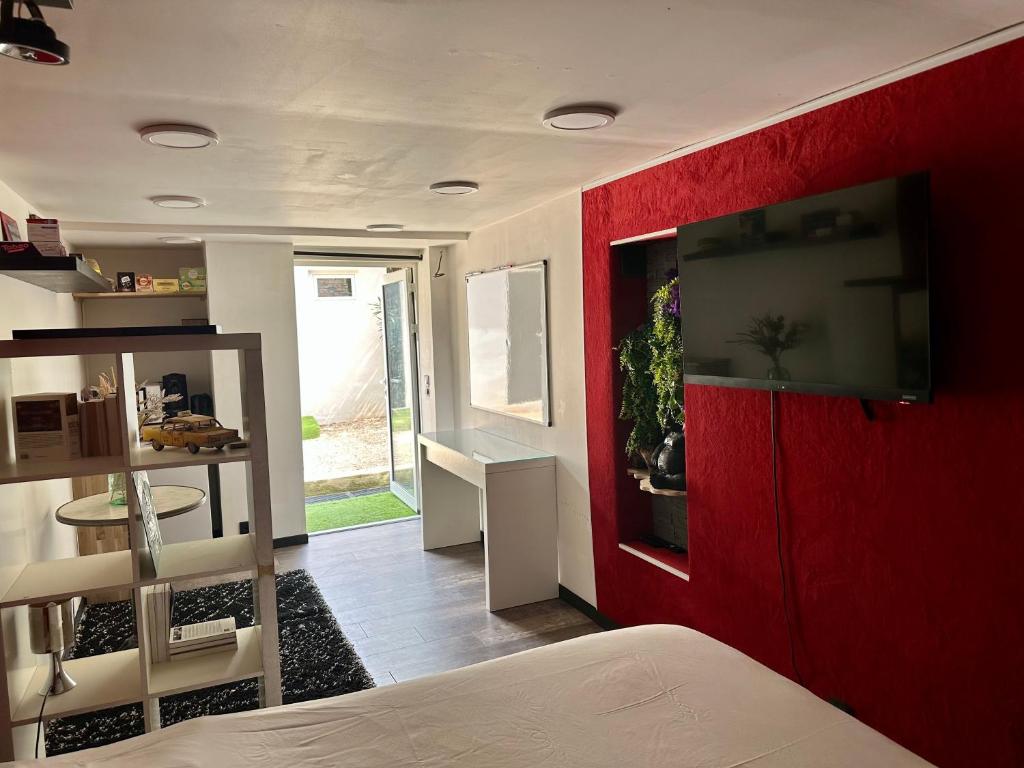 een slaapkamer met een rode muur en een flatscreen-tv bij STUDIO BIBOUNE in Ceyreste