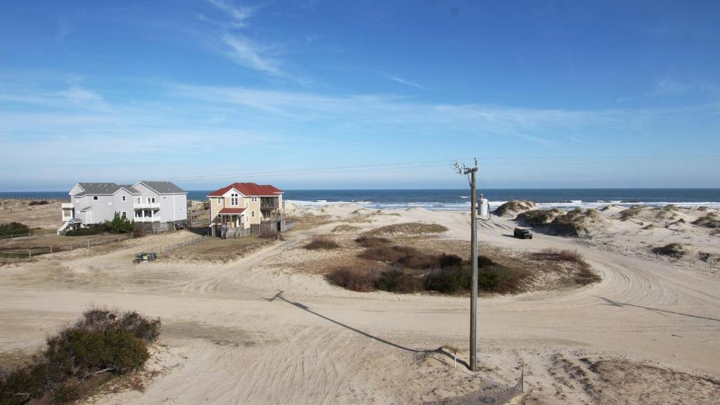 a couple of houses on a beach with the ocean at Semi-Oceanfront, Wild Horses, Hot Tub, Ocean Views! 4x2000, Sandfiddler Inn in Knotts Island