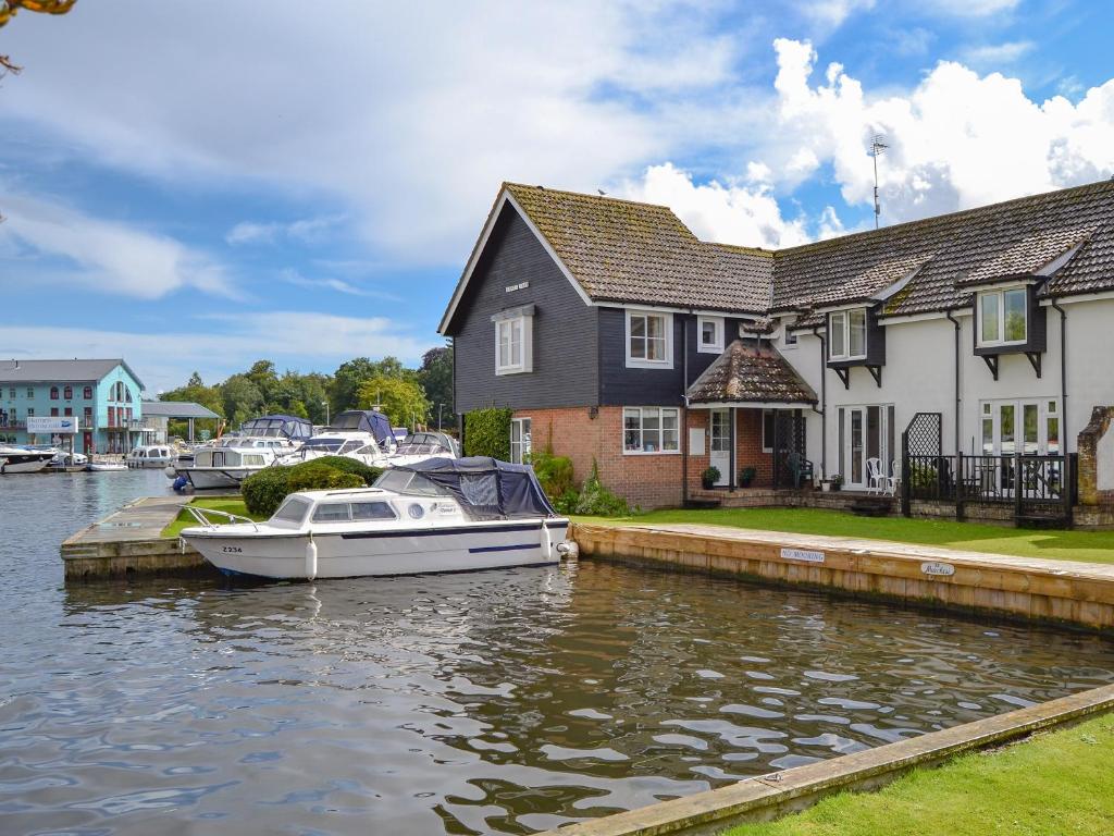 a boat docked in a marina next to a house at Nightingale in Wroxham
