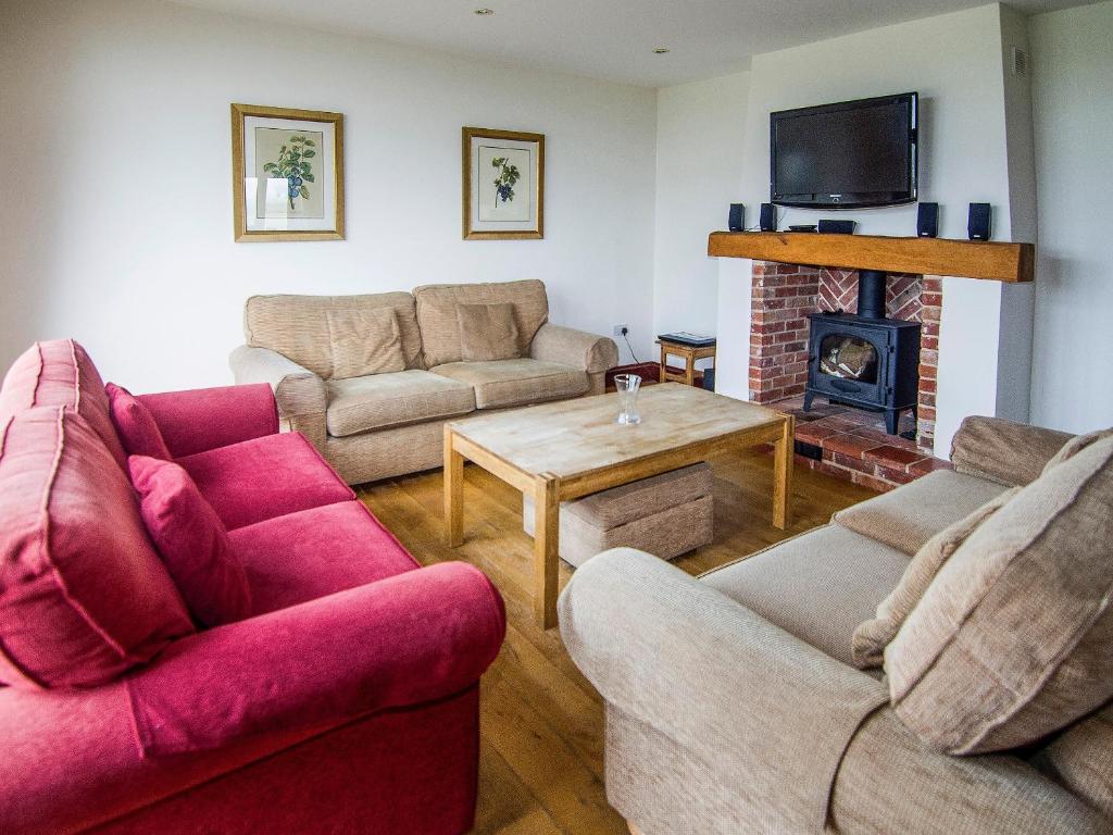 a living room with two couches and a fireplace at Kingfisher Barn in Sculthorpe