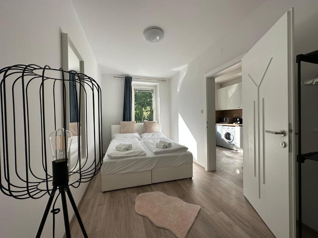um quarto branco com uma cama e um tripé em FeelHome-GolfClub-Balkon-4 Gäste-WiFi-Smart TV em Ebreichsdorf