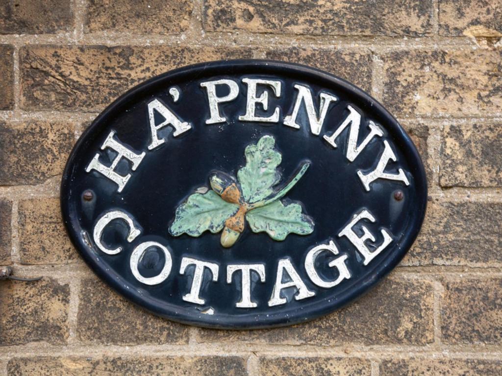 a sign on a brick wall with a pennant on it at Half Penny Cottage in Docking