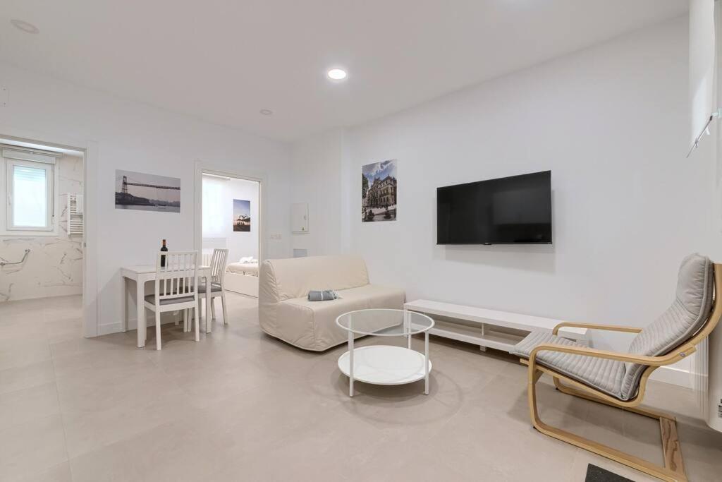 ein weißes Wohnzimmer mit einem Sofa und einem TV in der Unterkunft Unamuno Old Town 1 Free Parking in Bilbao