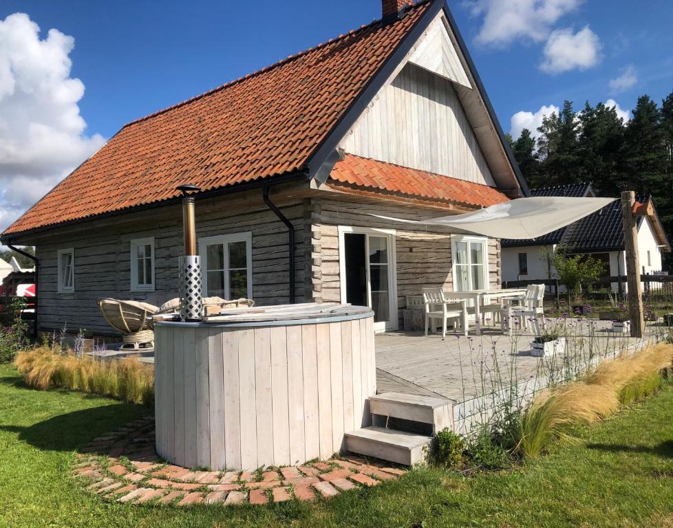 ein kleines Haus mit einer Terrasse und einem Sonnenschirm in der Unterkunft Dom z Bieszczad na Kaszubach - całoroczny dom z balią ogrodową in Kowalewo