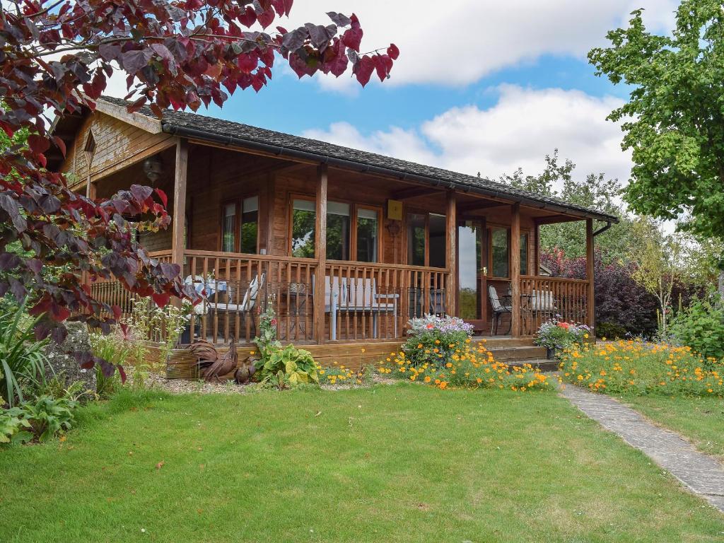 a log cabin with chairs and flowers in the yard at Lakeside Cabin in Kingston Blount