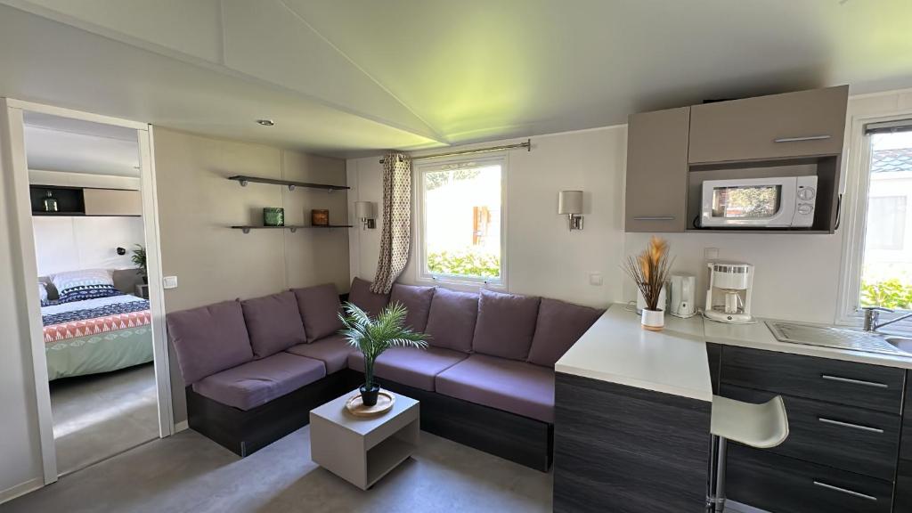 Il comprend un salon avec un canapé violet et une cuisine. dans l'établissement MobilHome 2 chambres 229 dans Camping 4 étoiles, à Pont-Aven