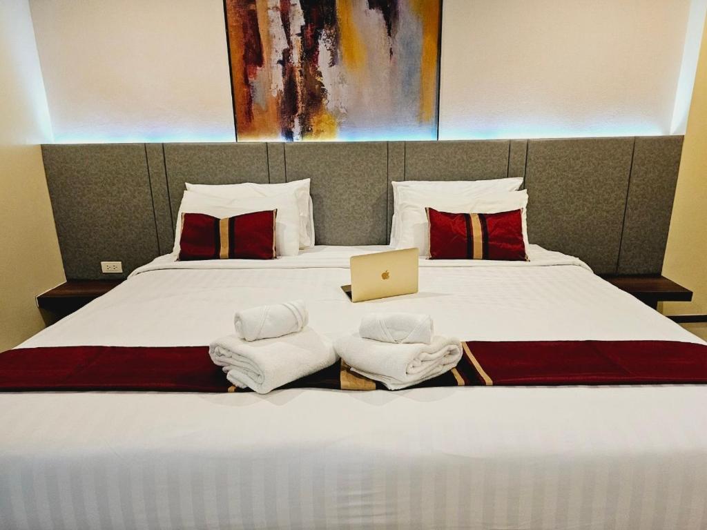a bedroom with a large bed with a laptop on it at STAYHERE@AIRPORT SERVICE APARTMENT in Ban Bo Han